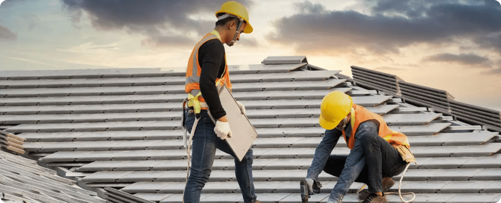 Licensed Alabama roofing contractors using professional tools and safety equipment to install a new tile roof on a construction site.