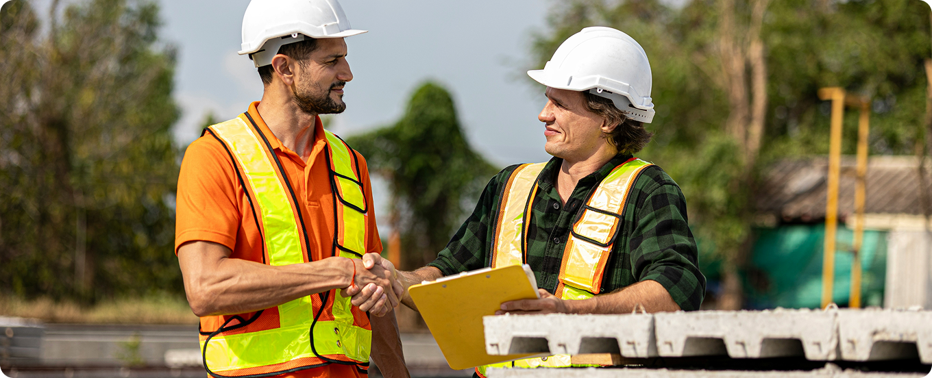 General contractor and qualifier shaking hands to finalize a contractor qualifier agreement on a construction site.