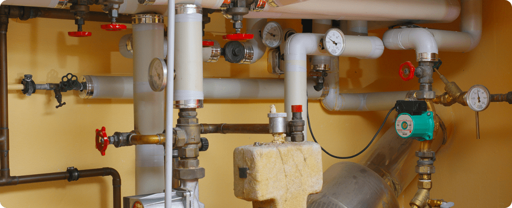 Professional plumbing installation and water management system with industrial-grade piping and temperature monitoring gauges.